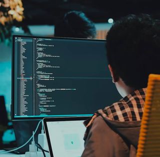 A person working at a computer screen full of text and code.
